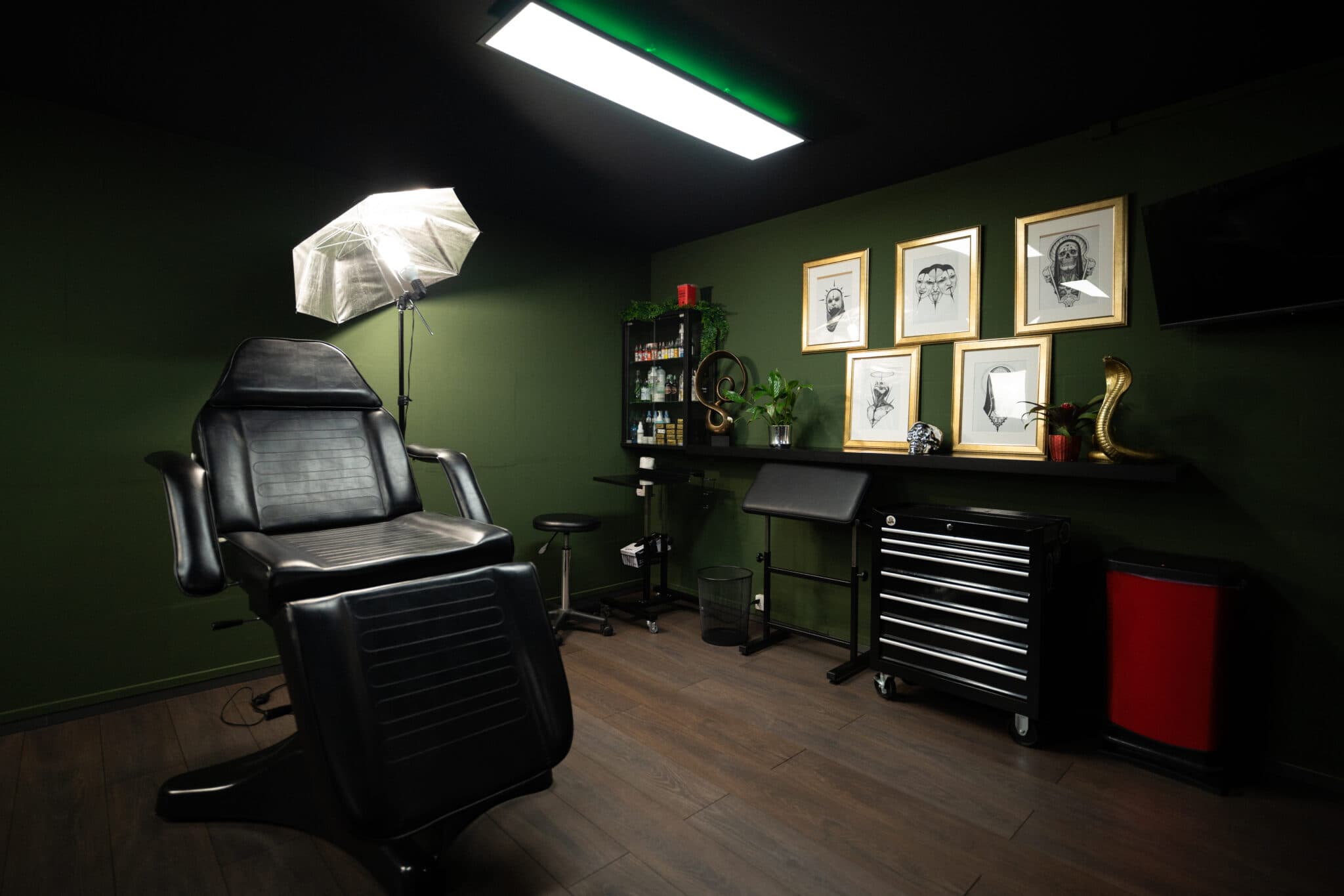 Tattoo-Raum bei INK ZONE ZÜRICH mit Behandlungsstuhl, Arbeitsfläche und gerahmten Entwürfen